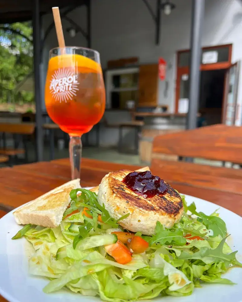 Grilovaný hermelín s brusinkami a Aperol spritz na stole terasy