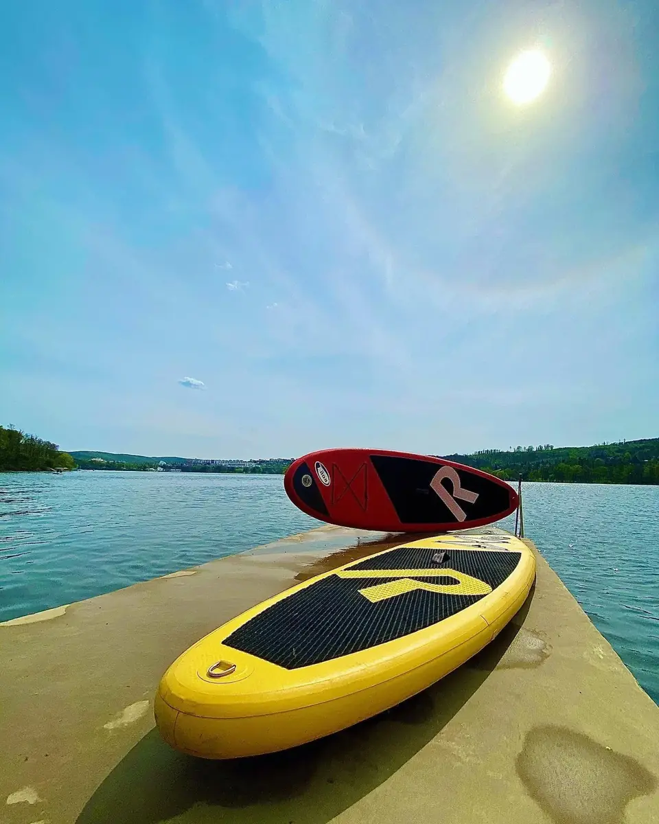 Paddleboardy na molu u Sokolského koupaliště, za nimi hladina Brněnské přehrady